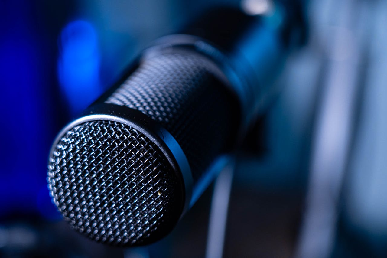 services-01 Detailed close-up of a professional studio microphone with a blurred blue background.